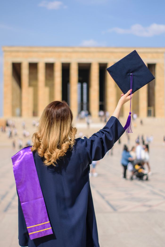A woman in a graduation gown holding a mortarboard at Anıtkabir, Ankara.